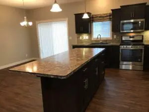 A kitchen with dark cabinets and wood floors