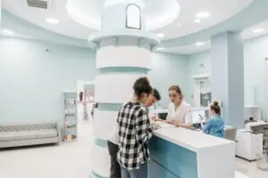 A woman is standing at the reception desk of a hospital.